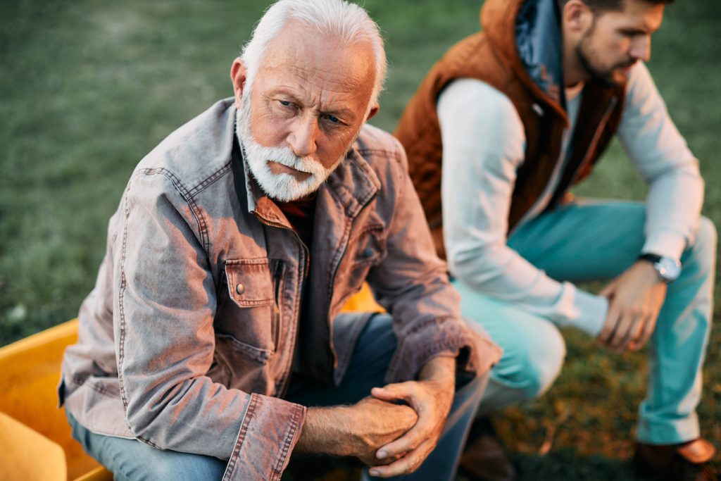 Displeased father sitting next to son