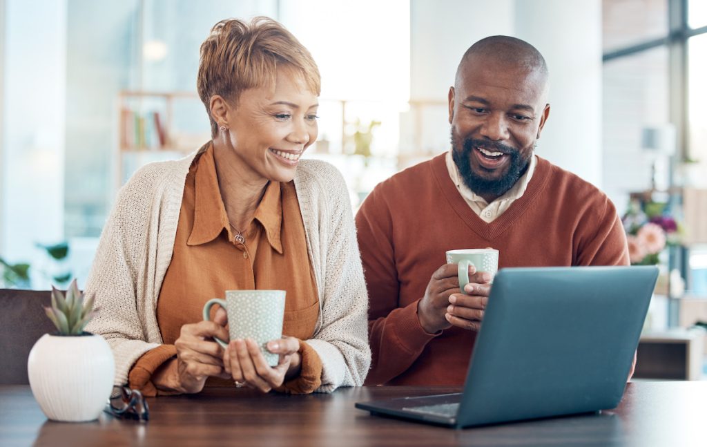 Mature couple drinking coffee while looking at computer