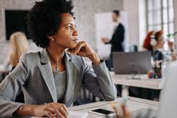 Professional woman looking thoughtful at work.