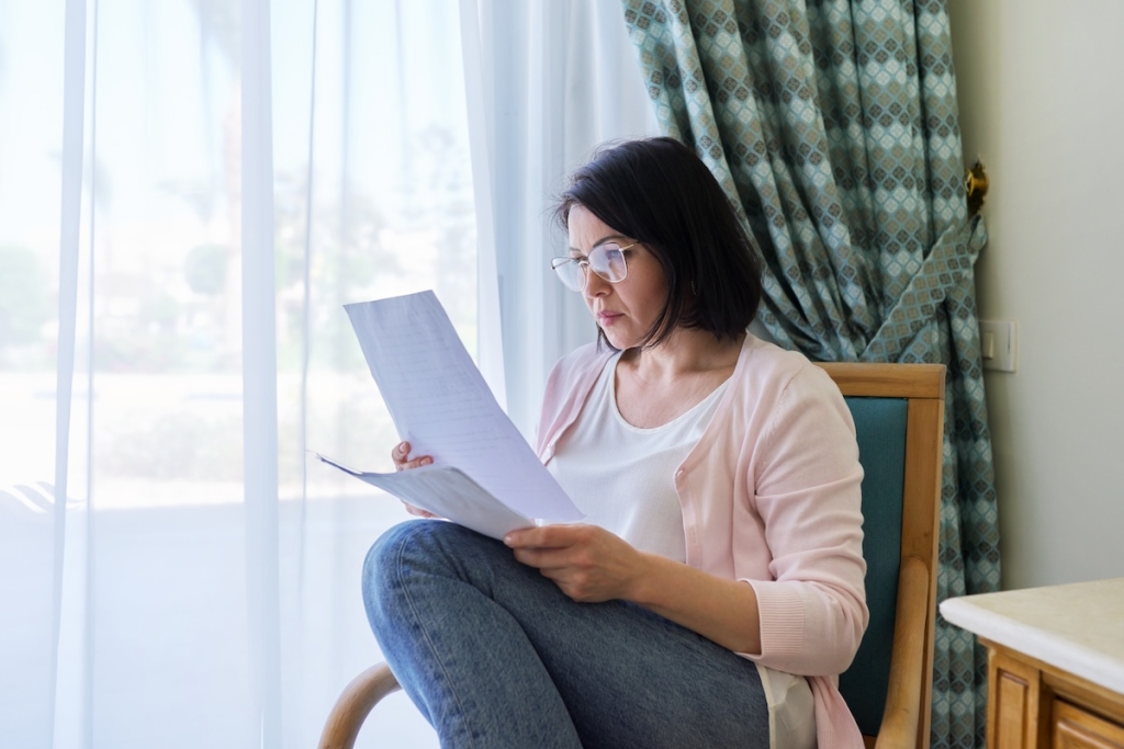 Woman sitting in chair looking at paperwork.