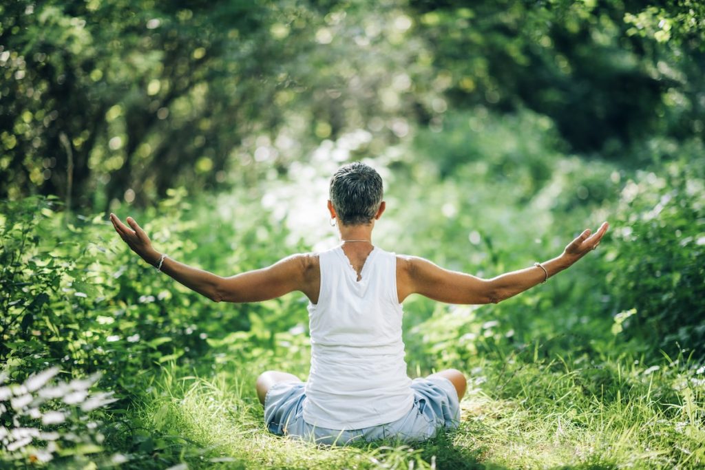 Women sitting in woods arms outstretched